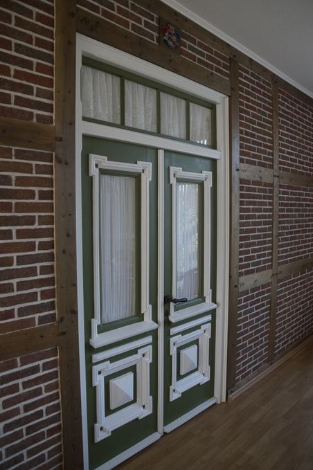 Historische grüne Tür im Dorfmuseum Ottenbüttel, eingerahmt von Backstein und Holz.