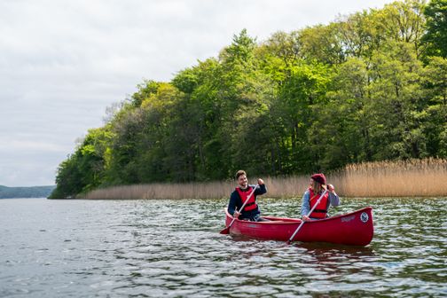 Zwei Menschen fahren in einem roten Kanu.