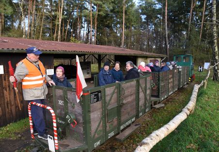 Kurbahn in Bad Bramstedt mit offenen Waggons, Fahrgästen und Zugführer im Wald.