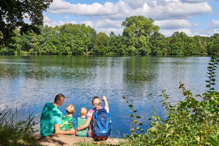 Familie sitzt am Ufer des Rensiger Sees und betrachtet das Waser