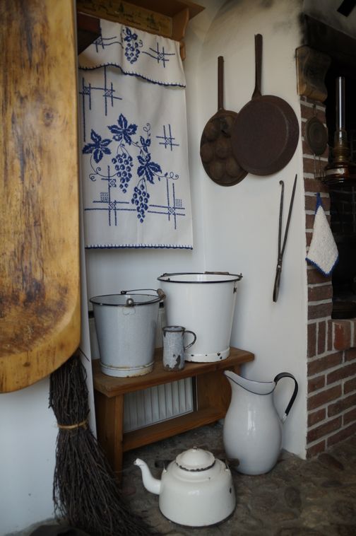 Historische Küchenecke im Dorfmuseum Ottenbüttel mit Emaille-Krügen, Kupferpfannen und traditionellem Textil.