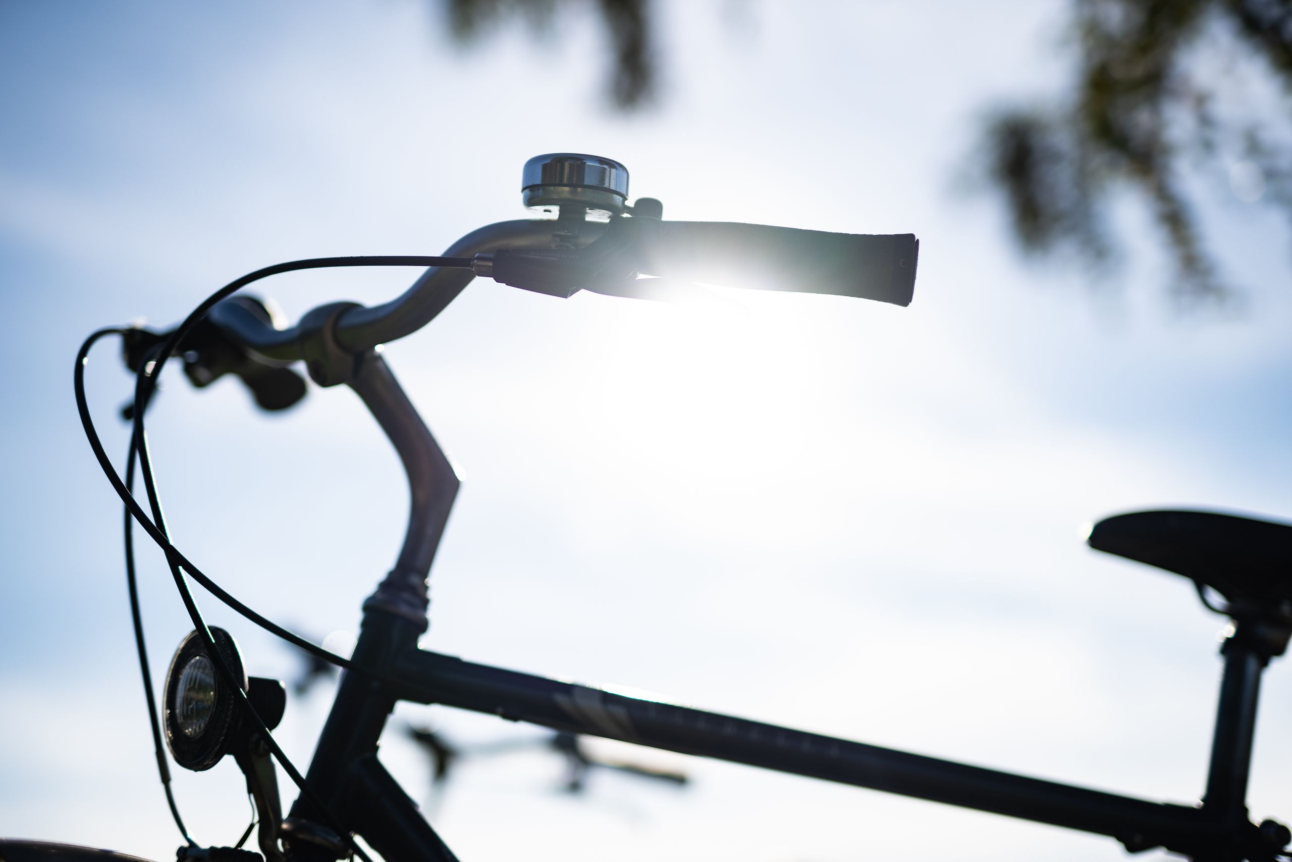 Ein Fahrradlenker im Gegenlicht der Sonne, das Licht strahlt durch die Griffe. Der Himmel ist klar und blau.