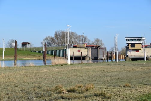Das Pinnau-Sperrwerk mit Schleusenanlage, Deich und Kontrollgebäude an einem klaren Tag.
