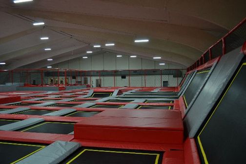Die Trampolinhalle „Jumping Point“ zeigt zahlreiche Trampoline mit roten Polstern in einer großen, hell beleuchteten Halle.