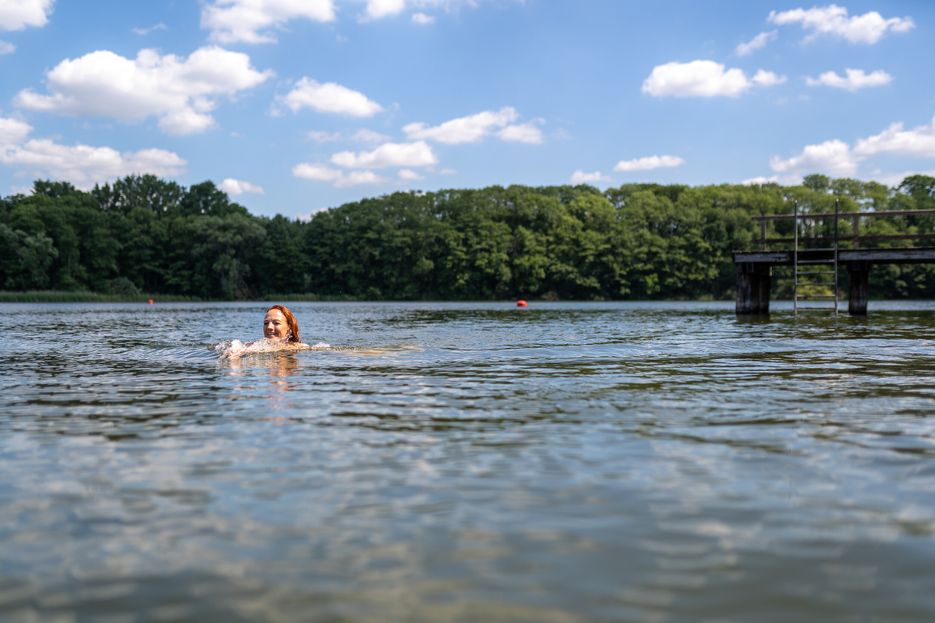 In einem See schwimmt eine Person. Zu sehen ist nur der Kopf.