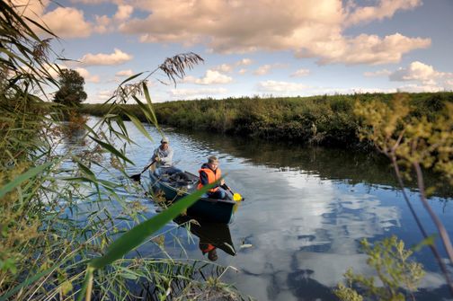 Kanufahrer entspannen bei einer schönen Tour auf der Wilsterau bei schönem Himmel mit rosa Wolken.