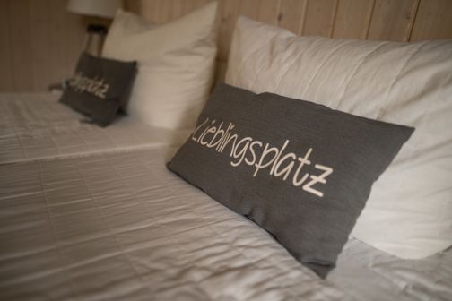 Bild von einem Bett mit einem Kissen, auf dem Lieblingsplatz steht.