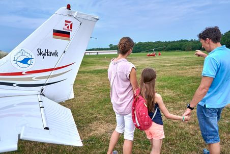 Familie auf dem Flugplatz Hungriger Wolf bei Hohenlockstedt neben einer Cessna Skyhawk, im Hintergrund ein roter Tragschrauber.
